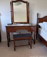 Full view of wooden vanity with attached mirror and matching stool, showing overall design, materials, and finish.