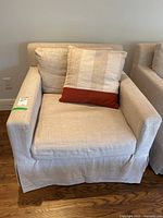 Front-facing view of beige armchair with throw cushion