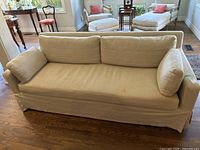 Front view of beige slipcovered sofa in living room