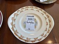 Two Bunnykins plates shown stacked with a tag indicating lot number and Bunnykins name visible, highlighting quantity and branding.