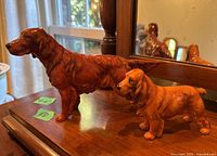 Two Royal Doulton dog figurines on a wooden surface with a mirror background