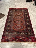 Full view of the rug laid out on a tiled floor showing overall design and condition.