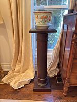 Wooden stand with Japanese ceramic pot and dish placed on top, showing the front view by window with natural light.