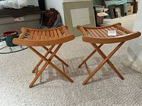 Pair of wooden folding slatted camp stools standing open on a carpeted floor in a basement room.