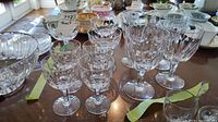Photo showing entire set of 4 goblets, 3 champagne glasses, and 4 wine glasses on a table with other household items in background.