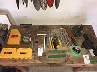 Overview of tools laid out on wooden bench including Dewalt cases, hand tools, tape, and vise grips
