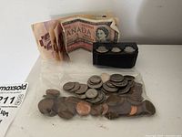 Mixed Canadian dollar bills, small black coin container, and bag of Canadian coins