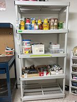 Full view of plastic utility shelving with various paint cans, tools, and containers on shelves, not included in sale.