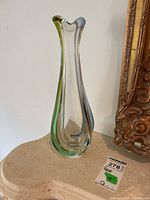 Front angled view showing the elongated, clear glass vase with green and blue color accents.