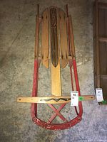 Top view of vintage Baycrest sled showing wooden seating slats with Baycrest logo and red metal frame