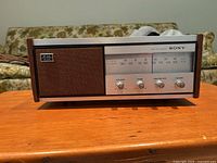 Front view of vintage Sony AM/FM radio showing the speaker on the left and dial/controls on the right with wood side panels.
