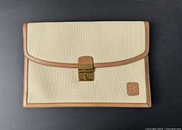 Front view of vintage Bally briefcase portfolio showing beige textured material with brown leather trim and gold-tone lock.