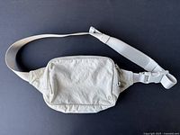 Front view of the light gray Lululemon waist bag with zipper closed and visible strap.