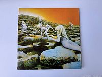 Front cover of the vintage Led Zeppelin 'Houses of the Holy' vinyl album shows iconic artwork of naked children climbing rocks under an orange sky.