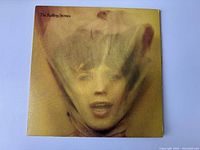Front cover of the vintage Rolling Stones vinyl album showing a face wrapped in translucent material with some age wear.