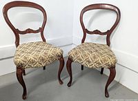 Pair of antique balloon back chairs with wooden frames and diamond-patterned floral upholstery.
