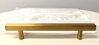 One brass drawer pull unpackaged showing rectangular bar and two round mounting legs