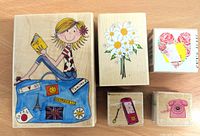Front view of all five stamps showing the colorful design on the wood mounts, including a girl reading a book on a suitcase and flower and phone illustrations.