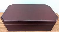 Closed view of the mahogany finished rectangular jewelry box with beveled edge lid.