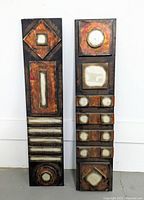 Two tall metal wall decor panels, each with geometric shapes arranged vertically, front view showing colors and texture.