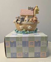 Front view of ceramic Noah's Ark money bank showing Noah and animal figures on the ark sitting on box