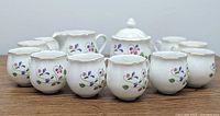 Front view of the set showing 10 teacups arranged in front with sugar bowl and creamer behind