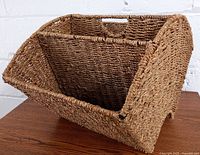 Front angle view of the seagrass magazine rack showcasing the open top with a built-in handle and four interior compartments.