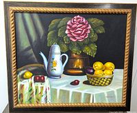 Front view of the still life oil painting showing pink rose, white teapot, lemons, cherries, and detailed cloth on table.