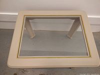 Top view showing rectangular glass insert with gold trim on cream coloured side table.