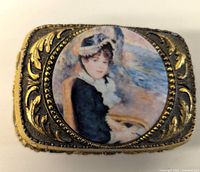 Top view showing painted portrait of a Victorian lady inset in round frame on the lid of the ornate gold-tone box.