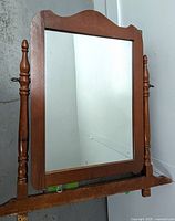 Full front view of the vintage wooden swivel dresser mirror highlighting the wooden frame with side spindles and mirror surface.