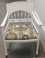 Front angle showing full chair with white wood frame, upholstered seat and caster wheels on legs.