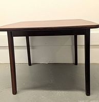 Side view of the wooden children's table showing four straight legs and rectangular top with rounded corners.