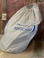 White AeroBed drawstring storage bag containing the mattress, showing brand logo.