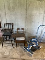 Overall view of four antique childcare items including a high chair, writing desk chair, stroller, and wooden toys parts.