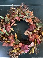 Autumn-themed wreath with artificial leaves and berries in fall colors