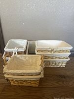 Seven woven baskets of varying sizes lined with white fabric, grouped in three sets for organizing