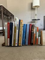 View of books arranged in wooden adjustable sliding bookends on a surface with a lamp in the background