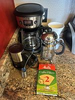 Mr. Coffee automatic drip coffee machine, French press, coffee filters, tea leaf diffuser, and milk frother base on kitchen counter