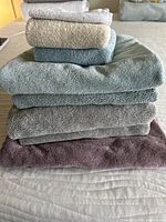 Stack of six towels in various colors and sizes showing texture and condition.