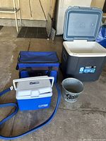 Photo showing all items together: gray Igloo cooler, blue soft cooler with shoulder strap, small EB Ice cooler, and metal Coors Light bucket.