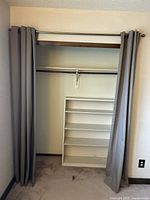 Curtain panels pulled to sides showing expandable silver curtain rod and closet interior