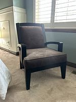 Dark wood armchair with brown suede seat cushion and fabric back, photographed from side angle in bedroom near window.