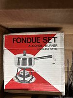 Box showing stainless steel fondue set with alcohol burner