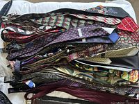 Over 50 assorted men's ties laid out showing various patterns and colors.