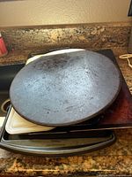 Round pizza stone with a seasoned, dark surface placed on countertop.