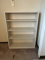 Front view of beige shelving unit showing 4 shelves with some wear and tear.