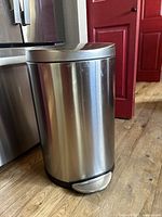 Front view of stainless steel Simple Human trash can showing pedal and body with surface scratches.