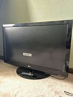 Front view of the LG 37-inch TV with remote on its stand showing 'No Signal' message on screen