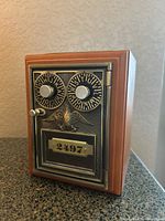 Front view of the coin bank showing the metal lockbox door with rotating combination dials, handle, eagle emblem and number plate '2497'.